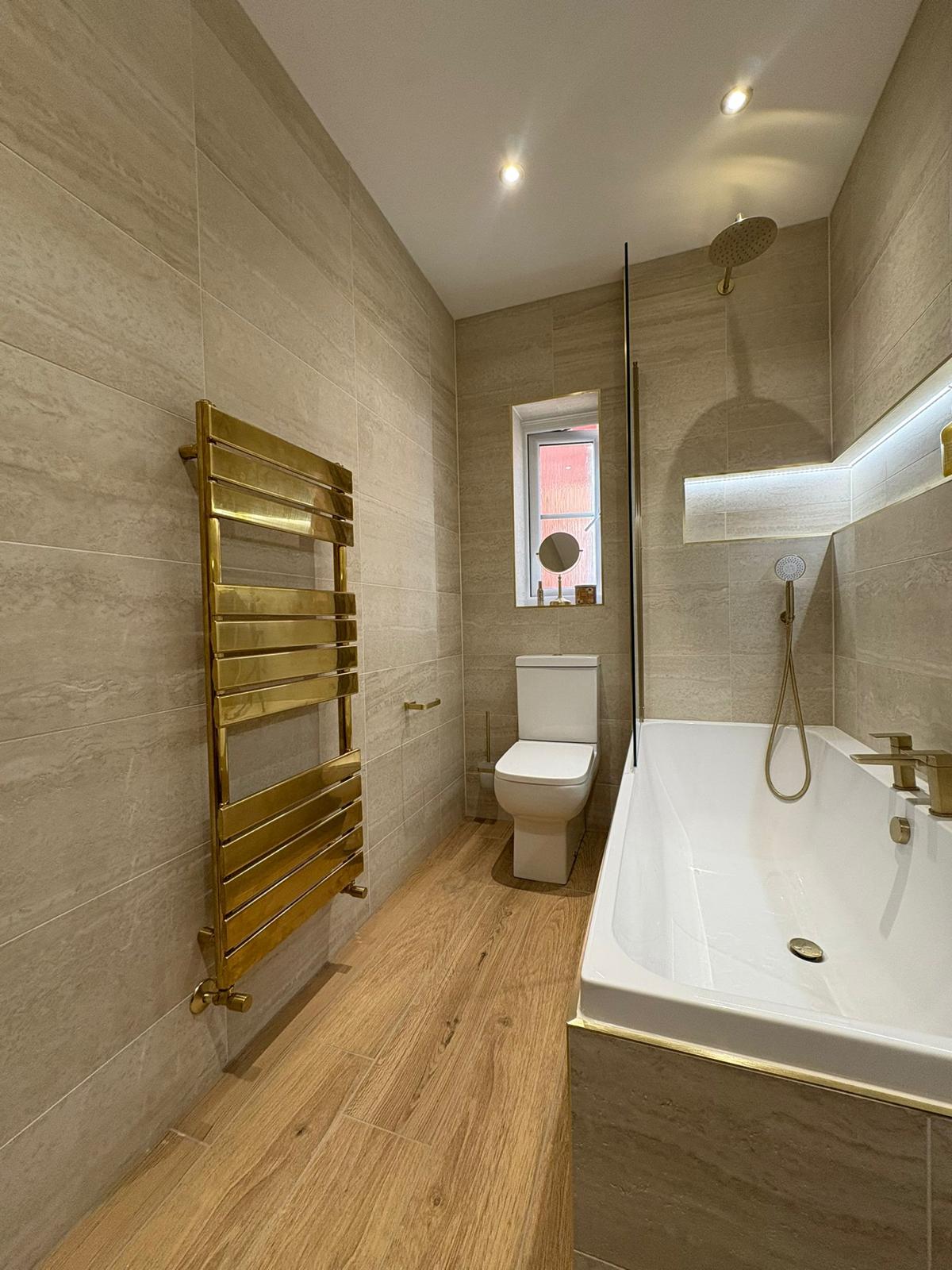 Gold heated towel rail in modern bath suite