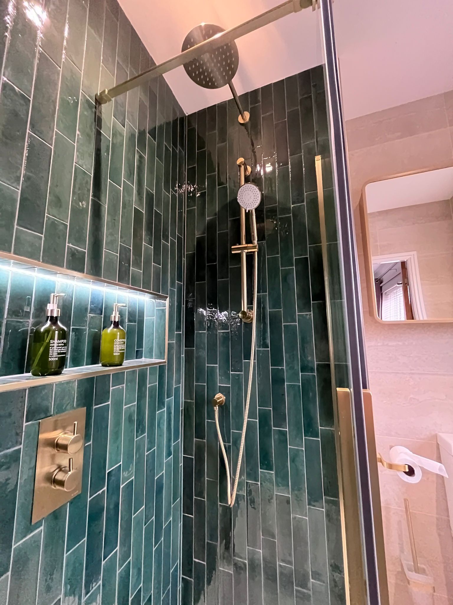 Teal tile walk-in shower with gold rainfall head
