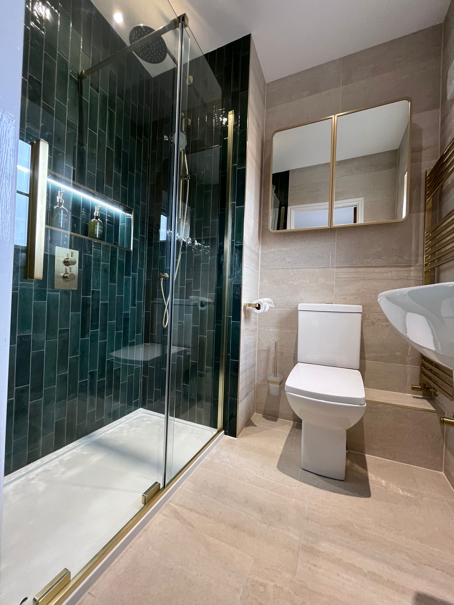 Teal tile shower enclosure with gold fittings